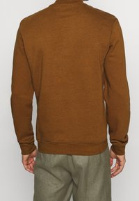 Brun sweatshirt med rund halsringning, ribbade ärmslut och kant. Tillverkad av mjukt tyg, som erbjuder en avslappnad och ledig passform.