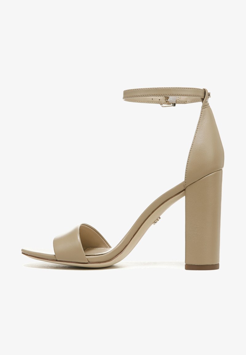 Beige hoge hakken sandalen met een gladde leren afwerking, een enkelbandje, open teen ontwerp en een blokhak voor stabiliteit.