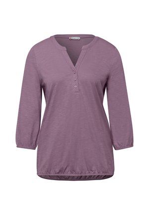Blusa de mujer de manga larga color lila con tres botones delanteros, puños elásticos y dobladillo fruncido.