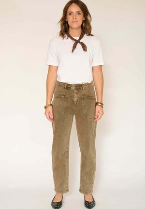 Pantalons en velours côtelé brun clair avec deux poches avant, une taille haute et une coupe droite, associés à un t-shirt blanc et des ballerines noires.