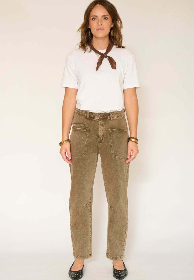 Pantalons en velours côtelé brun clair avec deux poches avant, une taille haute et une coupe droite, associés à un t-shirt blanc et des ballerines noires.