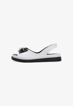 Biała skórzana sandałka typu slingback z czarną podeszwą i ozdobną czarno-złotą klamrą na przednim pasku.