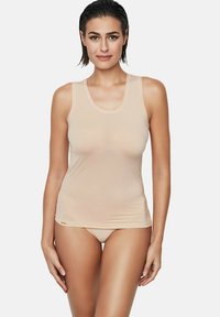 Débardeur beige sans manches au design ajusté, texture douce et léger éclat, avec un col arrondi et un branding minimal.