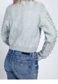 Light gray, textured knit sweater with a cropped design, embellished with decorative silver studs along the sleeves and hem.