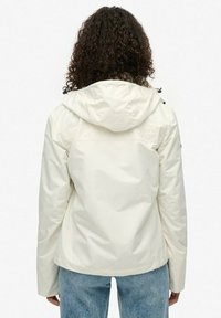 Hvid vandtæt jakke med hætte og justerbare snore, der har en glat tekstur og minimalistisk design. Velegnet til udendørs brug.