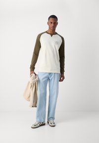 Pika-sleeve koor ja oliivroheline raglan särk, helesinised laiad teksad ja beez jakk, millel on drapeering. Igapäevased jalanõud roheliste, kreemjate ja pruunide aktsentidega.