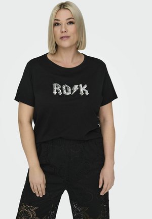 Schwarzes T-Shirt mit kurzen Ärmeln und rundem Ausschnitt, das auf der Vorderseite mit silbernen, verzierten Buchstaben "ROK" versehen ist. Getragen mit schwarzen gemusterten Hosen.