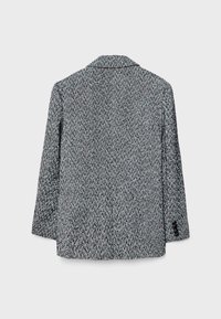 Blazer med fiskebensmønster i sort og hvid, med en notched krave og lange ærmer, lavet af tekstureret stof.