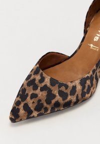Gros plan d'une chaussure à bout pointu en tissu imprimé léopard marron et noir avec une semelle intérieure beige rembourrée.