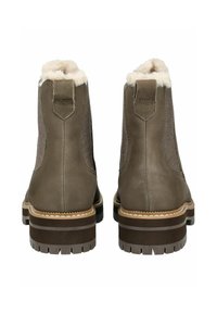 Braune Leder-Ankle-Boots mit einem plüschigen beigen Futter, strukturierten Seitenpanelen und einer robusten Sohle. Verfügt über einen kleinen Absatz und TOMS-Branding.