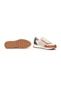 Zapatillas con una parte superior perforada en color crema, detalles en marrón y un talón azul marino. Suela de goma con un patrón de textura para mayor agarre.