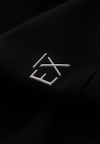 Tela negra con un logo blanco que presenta las letras "E" y "X" en un diseño minimalista y una textura suave.
