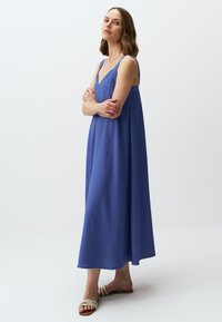 Vestito lungo senza maniche di colore blu con scollatura a V. Realizzato in un tessuto morbido, presenta una silhouette fluida e cade appena sotto i polpacci.