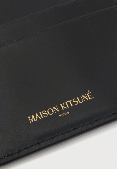 Μαύρος δερμάτινος θήκης καρτών με ανάγλυφο χρυσό κείμενο "MAISON KITSUNÉ PARIS". Ο σχεδιασμός περιλαμβάνει πολλαπλές θήκες καρτών και λεία υφή.