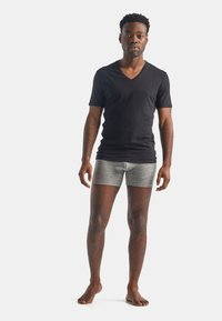 Svart V-hals T-skjorte kombinert med grå boxershorts. Stoffet virker glatt, og passformen er tettsittende, noe som fremhever en uformell stil.