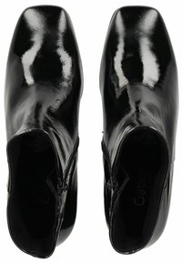 Bottes de cheville en cuir noir avec une finition brillante, bout carré, fermeture éclair sur le côté et doublure interne douce. Design minimaliste, sans motifs visibles.