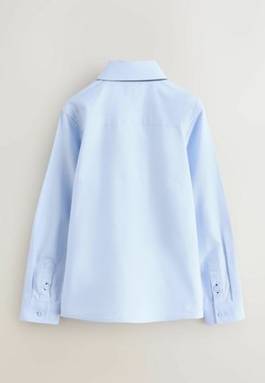 Vaaleansininen, pitkähihainen paita, joka on valmistettu sileästä kankaasta. Siinä on klassinen kaulus, napilliset kalvosimet ja suora selkäosa ilman näkyviä kuvioita.