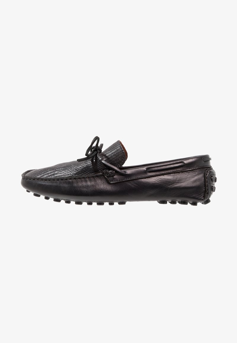 Mocassin homme en cuir noir avec dessus texturé, détail nœud et semelle en caoutchouc avec clous antidérapants pour un usage décontracté.