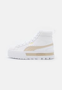 Vysoké tenisky z bílé kůže s béžovým logem Puma. Silná podešev s viditelnými drážkami a texturovanými akcenty v béžové barvě.