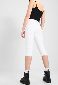 Valkoiset lyhyet farkut repaleisilla helmalla, korkea vyötärö ja takataskut, yhdistettynä mustiin maiharisaappaisiin ja mustaan topiin.