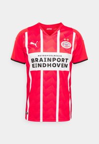 Maillot de football rouge avec des rayures verticales blanches et un motif en chevron, doté d'un col en V, d'un logo noir et d'un grand texte indiquant "BRAINSPOORT EINDHOVEN."