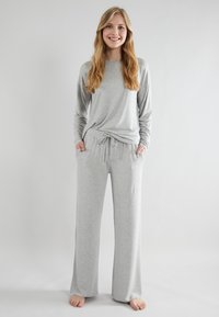 Grijs langmouwen top en bijpassende drawstring broekset gemaakt van zachte stof, met een relaxte pasvorm en zijzakken. Smooth textuur, minimalistisch ontwerp.