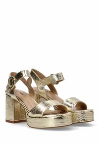 Sandalias de tacón metálico dorado con tiras anchas, una plataforma y puntera redonda. Presentan un acabado brillante y una correa ajustable en el tobillo con herraje redondo.