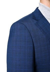 Granatowa marynarka w kratę, o gładkiej teksturze i wyraźnie zaznaczonych ramionach. Pod spodem widoczny szary golf.