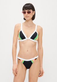 Čierny bikinový set s bielym lemovaním; trojcípová podprsenka a hipster nohavičky so farebnými horizontálnymi prúžkami v zelenej, oranžovej a ružovej farbe.