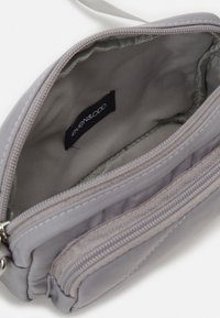 Borsa grigia con zip realizzata in tessuto morbido. Presenta un compartimento principale con una semplice fodera e un'etichetta, e una tasca esterna con zip.