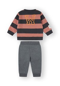 Conjunto para niño pequeño con suéter de manga larga a rayas negras y naranjas con una gran "W" en la espalda y pantalones grises lisos con puños acanalados.