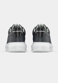 Μαύρα αθλητικά παπούτσια με γυαλιστερή επιφάνεια, λευκές σόλες και μαλακό γιακά, με τη σήμανση "KARL LAGERFELD" στο πίσω μέρος.