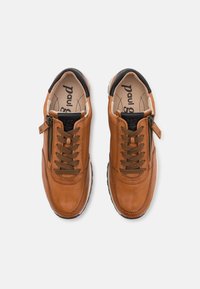 Baskets en cuir marron avec des accents noirs, présentant un design à lacets à l'avant, une fermeture éclair sur le côté, ainsi que des surfaces texturées et lisses.