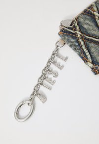 Denim zip pouch with orange stitching, silver hardware, and a chain featuring "DIESEL" in sparkling letters. Round keyring attached.