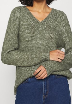 Maglione lavorato a maglia verde oliva con scollo a V, polsini a coste e vestibilità rilassata. Presenta un filato testurizzato e un orlo leggermente curvo.