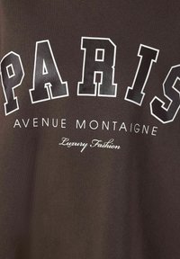 Tessuto nero con il testo "PARIGI" delineato in bianco in grandi lettere, il testo più piccolo sottostante recita "AVENUE MONTAIGNE" e in corsivo "Moda di Lusso".