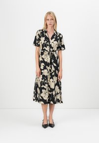 Robe midi noire à fleurs avec des manches courtes, une taille nouée et un devant à boutons. Présente un motif floral crème clair sur le tissu.