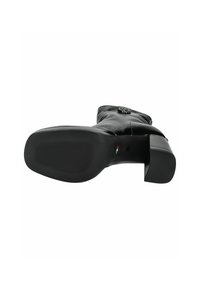 Stivale in pelle nera con suola testurizzata, tacco spesso e hardware decorativo sul lato. L'interno è liscio con cuciture visibili.