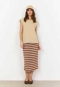 Beige short-sleeve top paired with a striped midi skirt in light brown and cream. The model wears a matching cap and black woven flats.