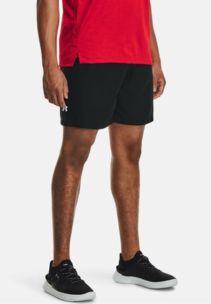 Pantalones cortos deportivos negros con diseño clásico, hechos de material ligero. Combinados con zapatos deportivos negros con suela texturizada. Camiseta roja.