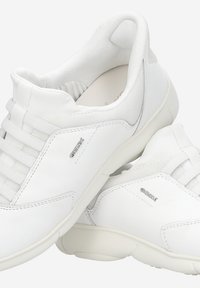 Baskets blanches avec côtés en cuir lisse et détails en mesh. Caractérisées par un laçage symétrique et un branding discret sur les côtés.