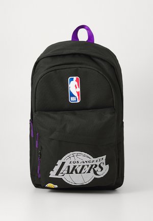 Black backpack with NBA logo and "Los Angeles Lakers" graphic. Features purple zipper accents and a top handle for carrying.