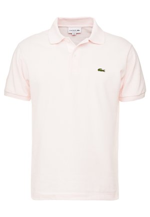 Jasnoróżowa koszulka polo Lacoste z krótkimi rękawami, kołnierzykiem, listwą na dwa guziki oraz małym zielonym haftowanym logo krokodyla na piersi.