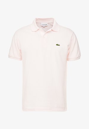 Polo Lacoste rose clair avec manches courtes, col, patte à deux boutons et petit logo crocodile vert brodé sur la poitrine.