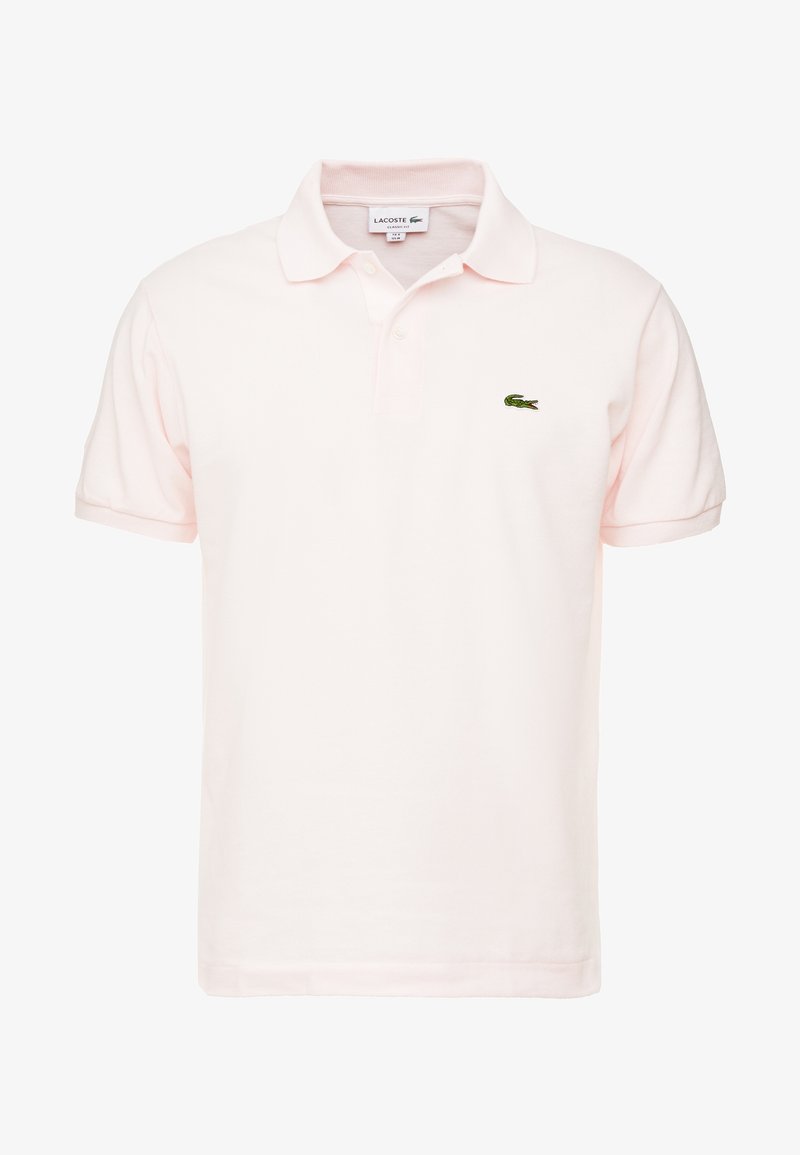 Polo Lacoste rose clair avec manches courtes, col, patte à deux boutons et petit logo crocodile vert brodé sur la poitrine.