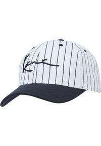 Hvit baseballcap med vertikale svarte striper, en marineblå skygge, og en signaturlogo brodert i svart på forsiden.