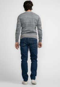 Grauer melierter Strickpullover mit Rundhalsausschnitt, gerippten Bündchen und Saum, kombiniert mit dunkelblauen Jeans und weißen Sneakers. Rückansicht.