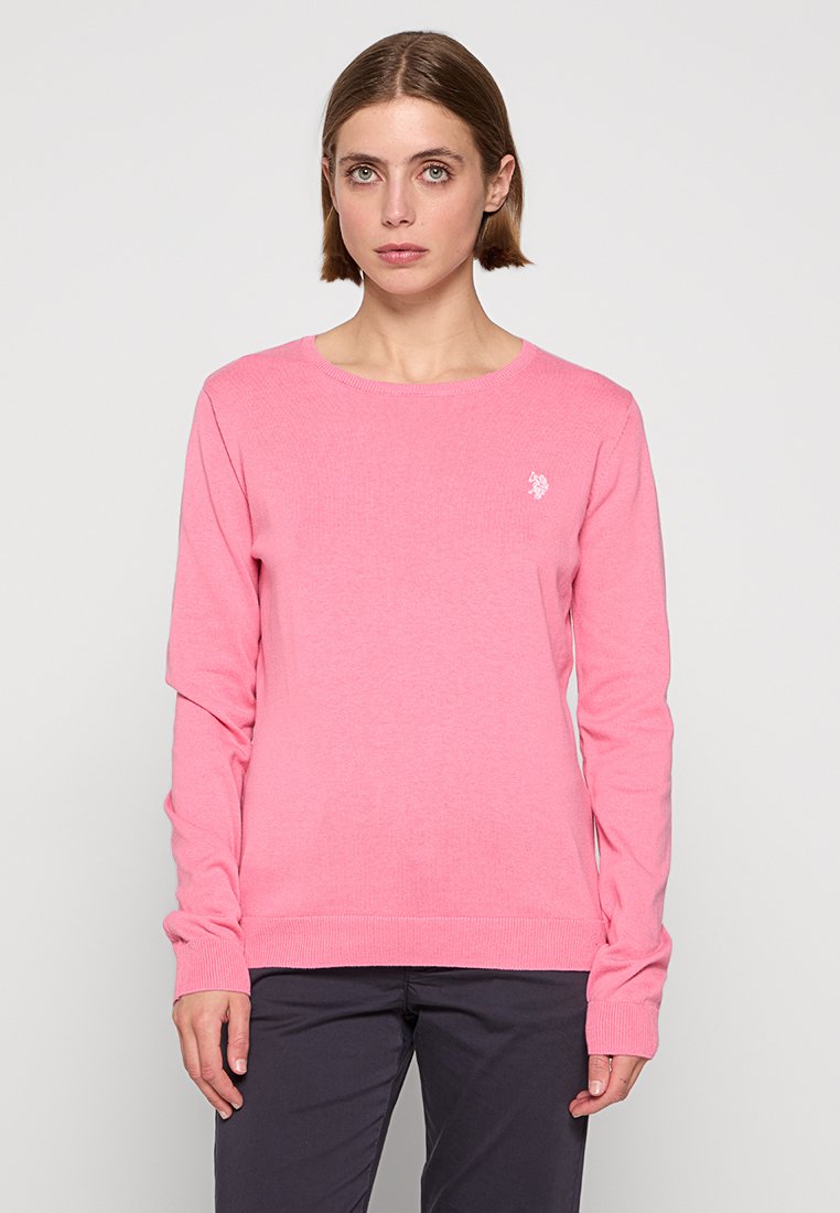 Maglione rosa a maniche lunghe in tessuto a coste con scollatura tonda e un piccolo logo bianco sul lato sinistro del petto. Orlo dritto.