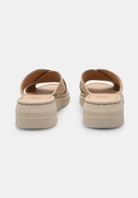 Sandales plateforme beiges avec de larges bretelles croisées, tige en cuir doux, semelle intérieure rembourrée et semelle en caoutchouc texturé pour une bonne adhérence.