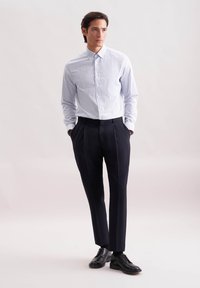 Koszula zapinana na guziki w jasnoniebieską i białą kratkę, zestawiona z dopasowanymi ciemnymi spodniami i czarnymi skórzanymi butami. Gładka faktura, standardowy kołnierzyk.